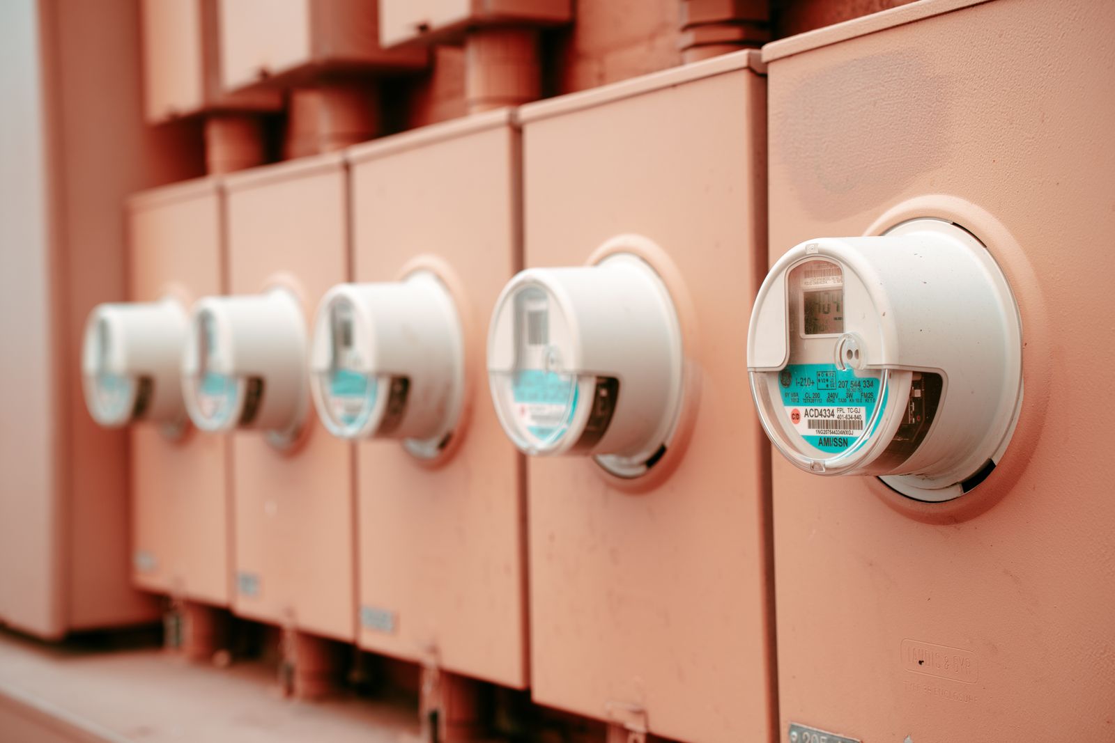 Řada elektroměrů na oranžové stěně rozvodné skříně bytového domu