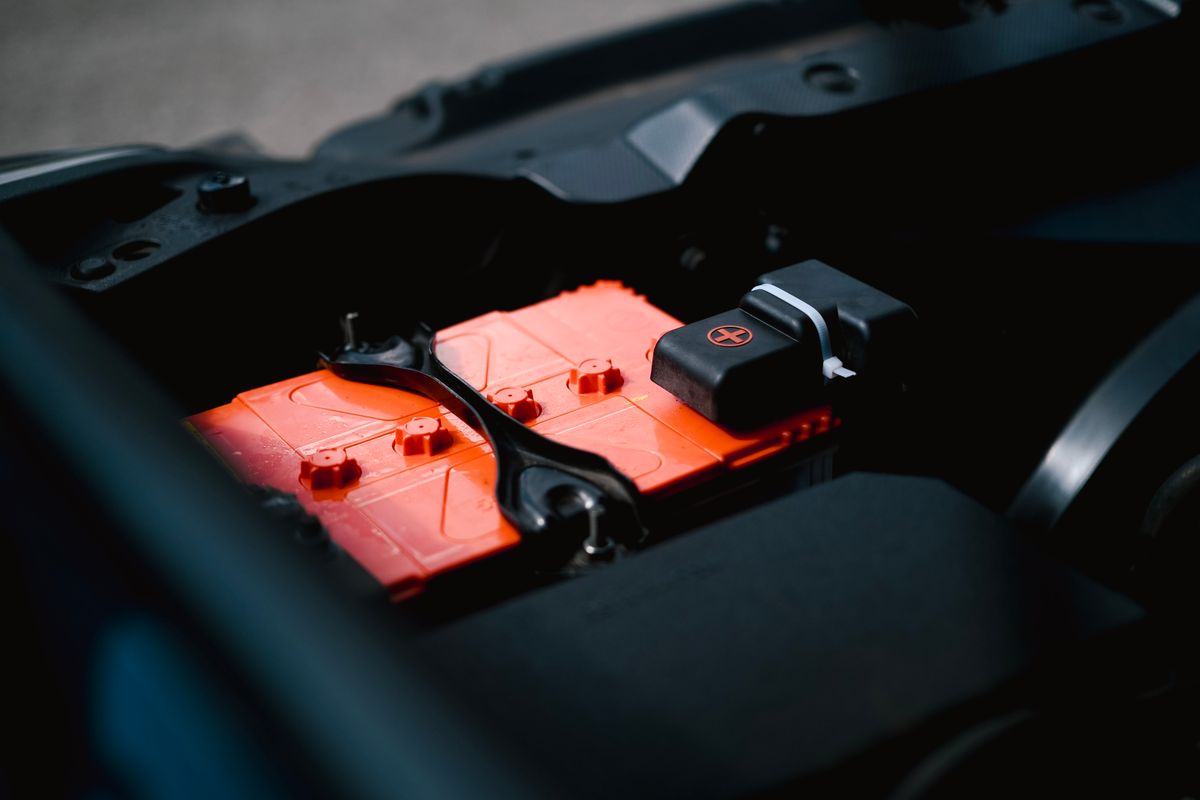 Autobaterie usazená v motorovém prostoru automobilu, detail pólů a svorek