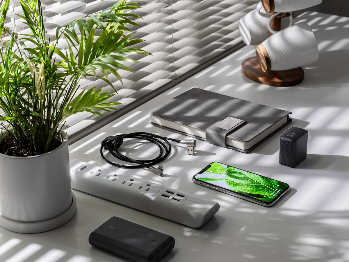 Wi-Fi router a kabely na stole vedle rostliny a telefonu